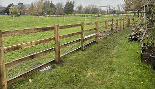 Wooden post-and-rail fence running along a grassy field