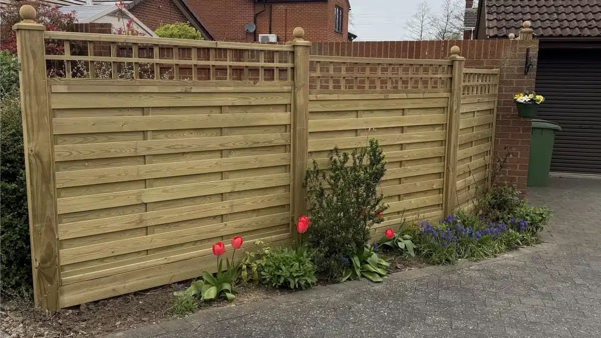 New wooden garden fence with flower border along a driveway
