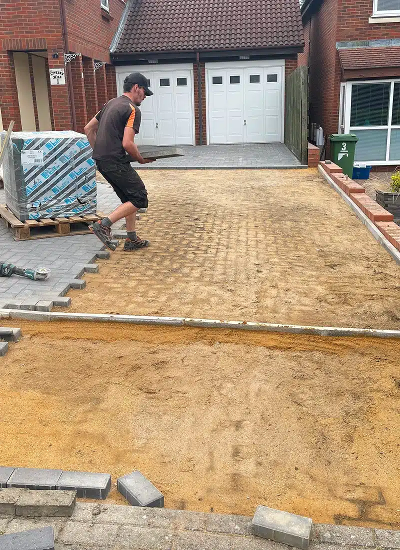Worker laying paving slabs on a driveway under construction