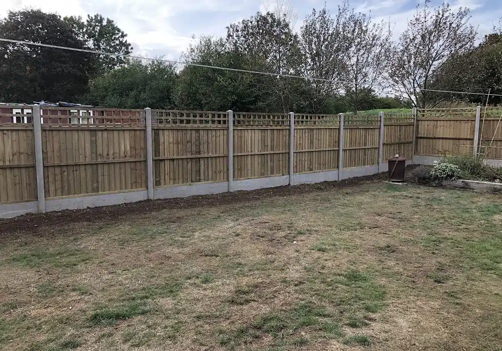Back garden with a wooden fence and patchy lawn
