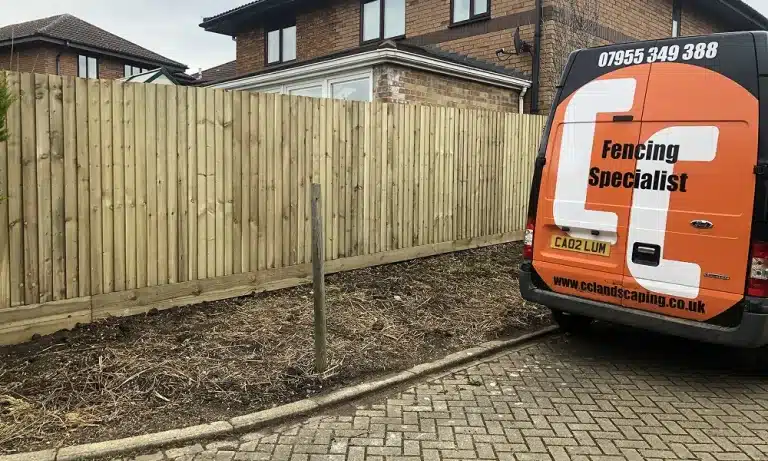 Van parked beside a newly installed wooden fence at a house