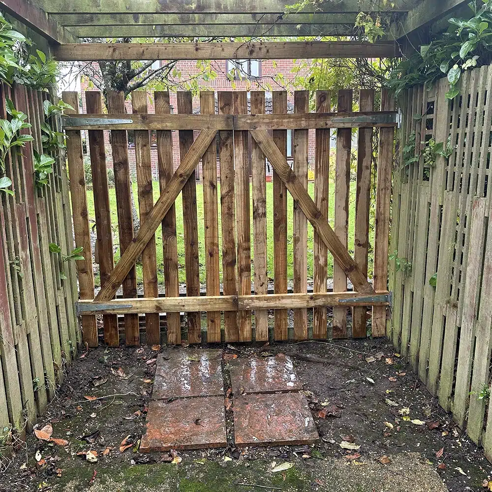 Wooden garden gate with trellis sides, closed and muddy ground in front