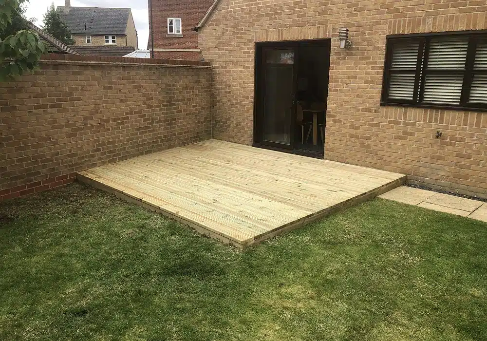 New timber deck in a back garden beside a brick house