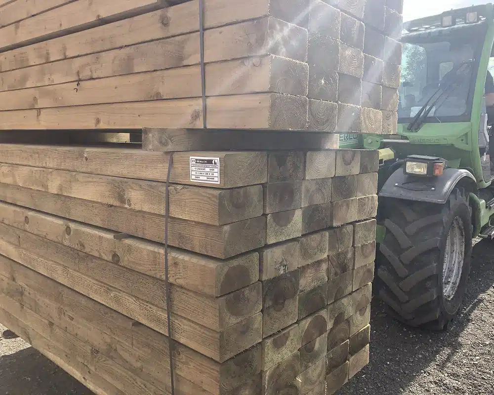 Stack of timber beams strapped on a lorry beside a tractor