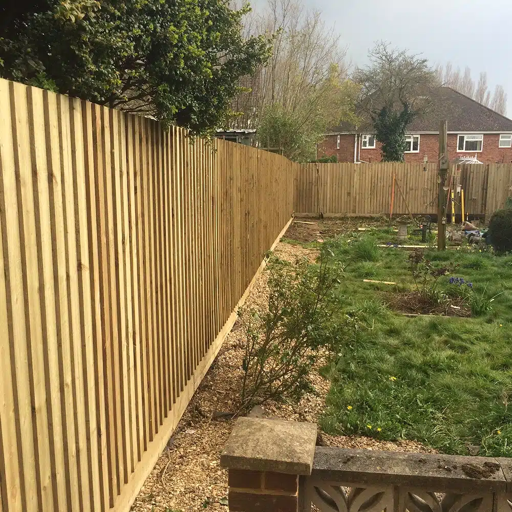 New wooden fence along a garden boundary with lawn and shrubs