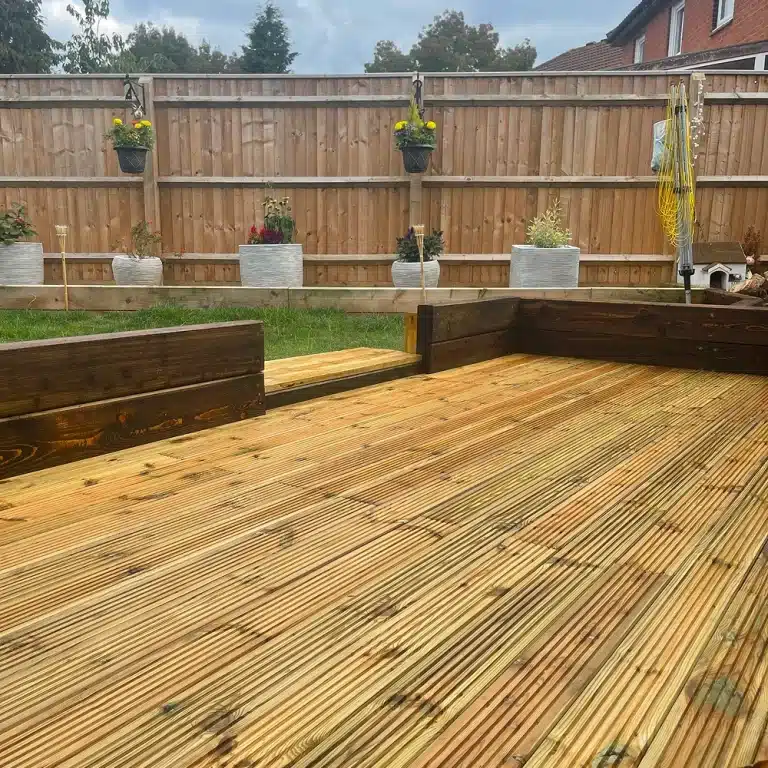 Wooden garden decking with raised planters and a fenced back garden