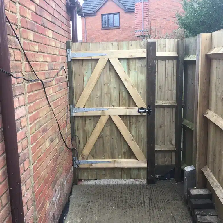Wooden garden gate between brick walls and fencing