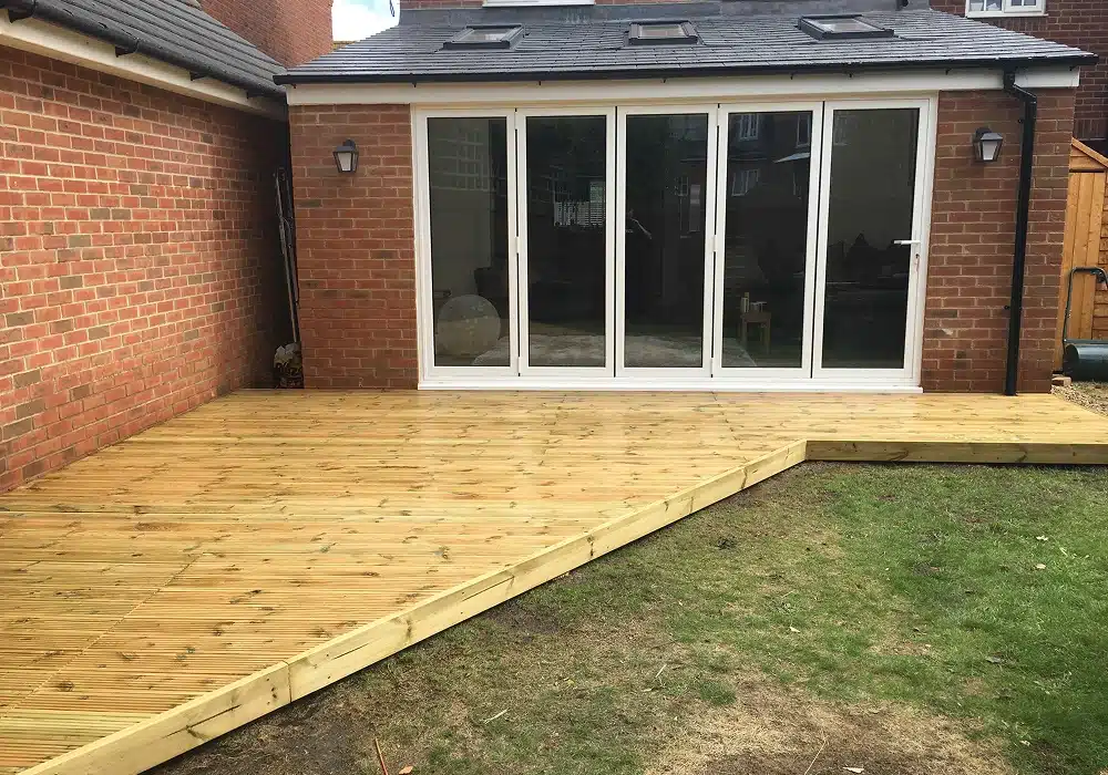 Wooden garden decking outside a brick house with bi-fold doors