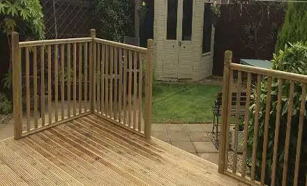Wooden deck with railings leading down to a garden path and shed